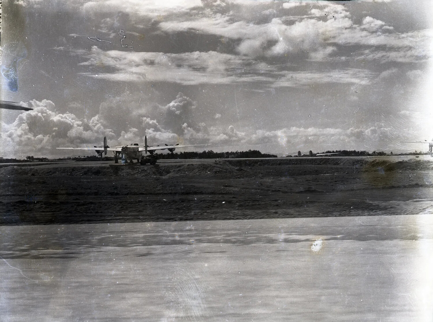 Twin-Engine Bomber Beyond Airfield Revetment Under Cumulus Sky, 345th Bombardment Group Base, WWII Pacific Theater