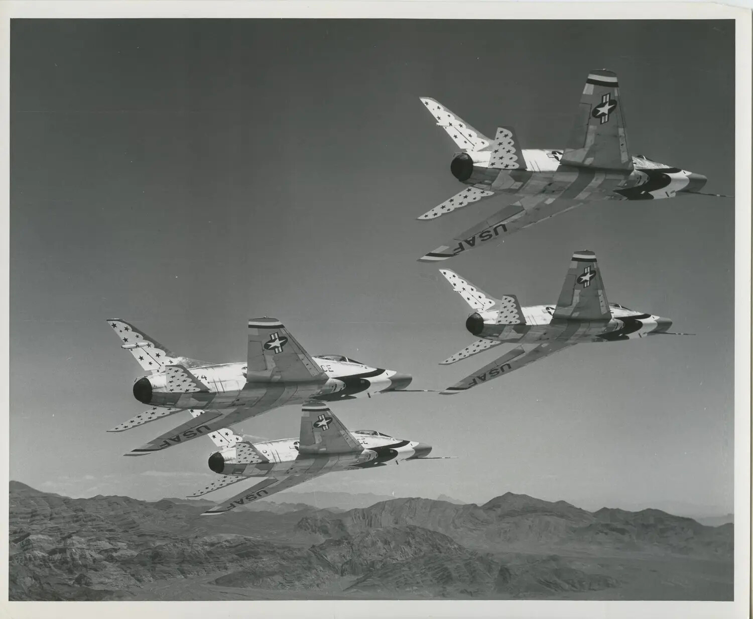 USAF Thunderbirds F-100 Super Sabres in Diamond Formation over Desert Terrain