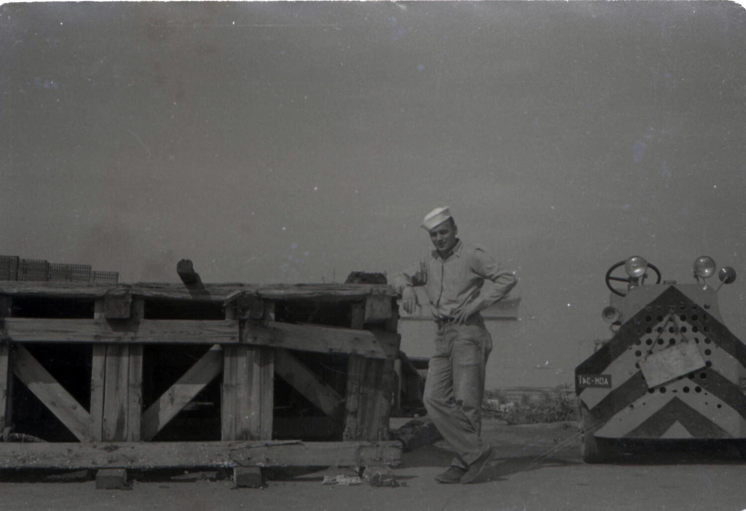 Sailor Posing by Shipping Crates and Utility Vehicle, USS Yorktown Collection