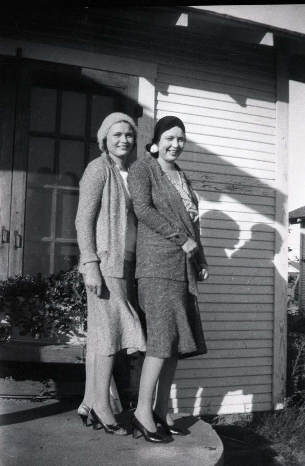 Two Young Women in 1930s Fashion Outside a Clapboard House
