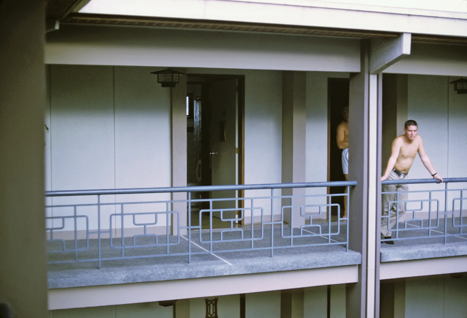 Two Men on Balcony Walkway of Asian-Style Hotel or Barracks Building
