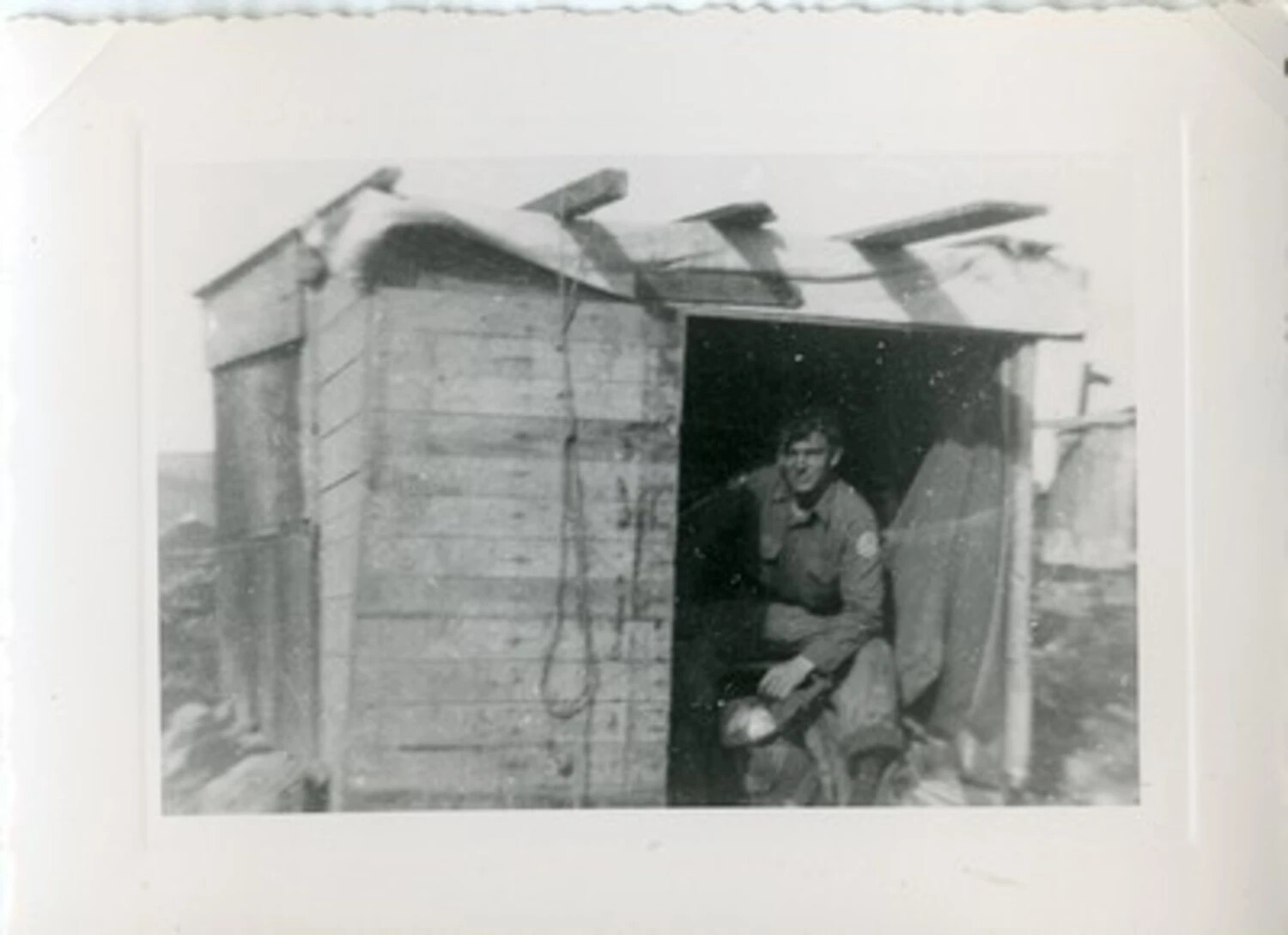 American Serviceman in Doorway of Wooden Field Shelter, Winter Scene -- Joe Vieira Collection