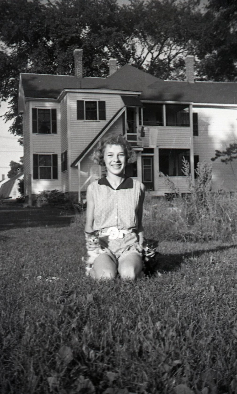 Young Woman with Two Cats Before a New England-Style Triple-Decker, c. 1940s