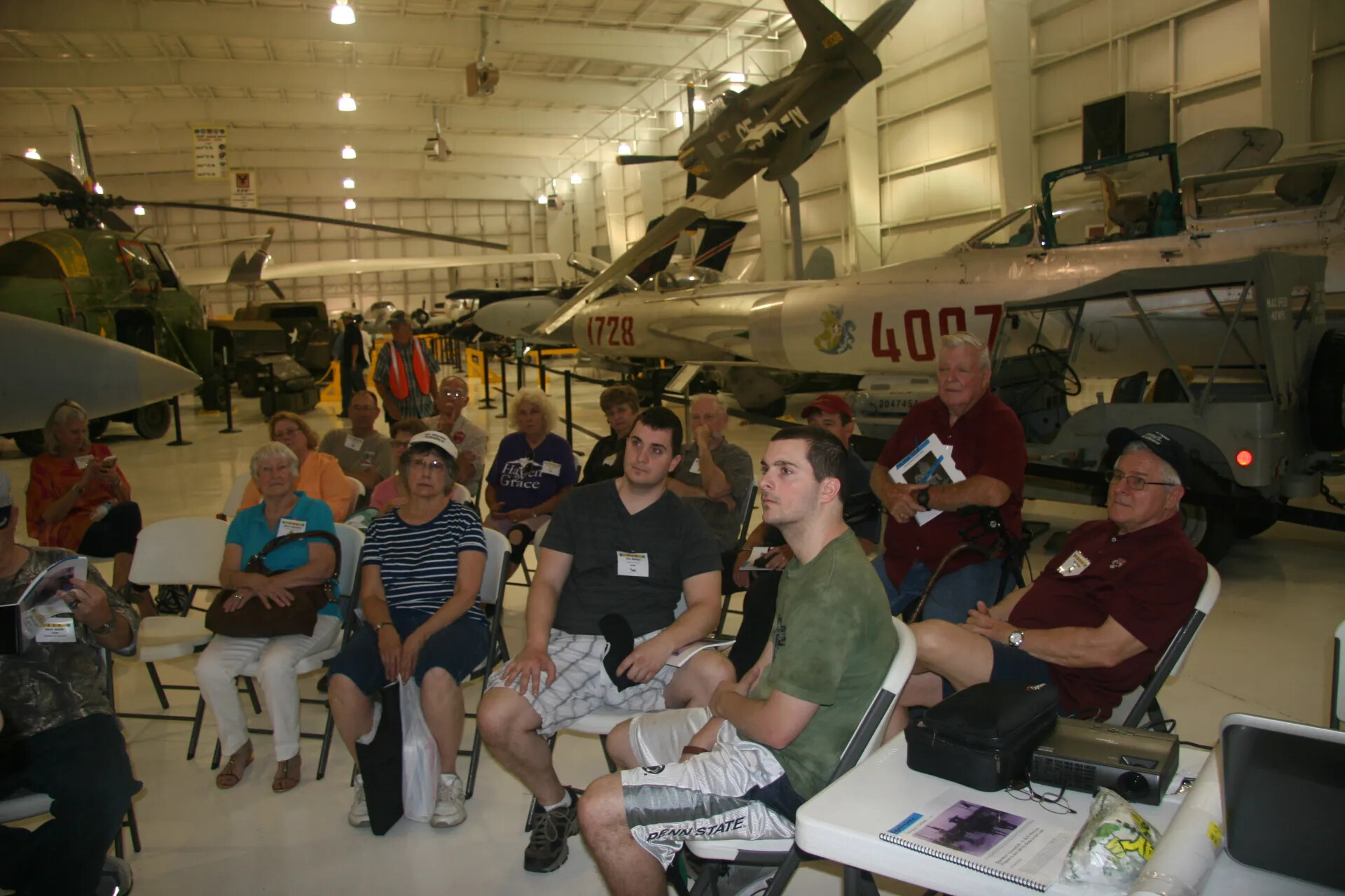 Reunion Audience Seated Among Cold War and Vietnam-Era Aircraft, Aviation Museum Hangar (Alternate Frame)