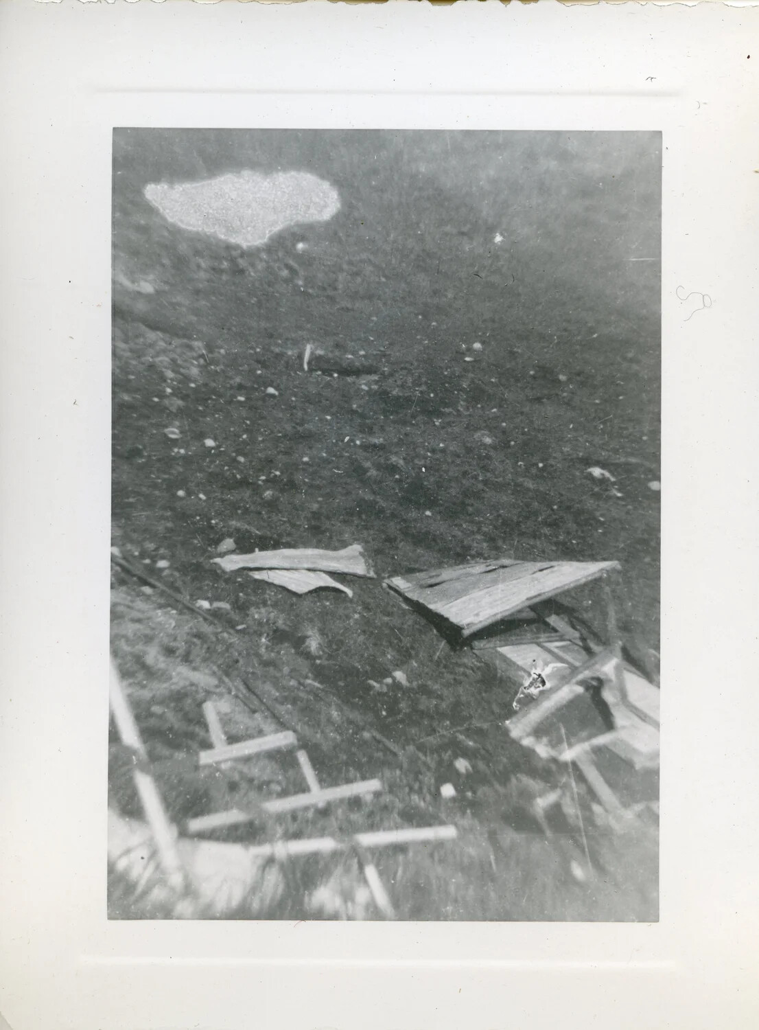 Scattered Wooden Debris and Improvised Markers on Disturbed Ground, Pacific Theater, World War II Era