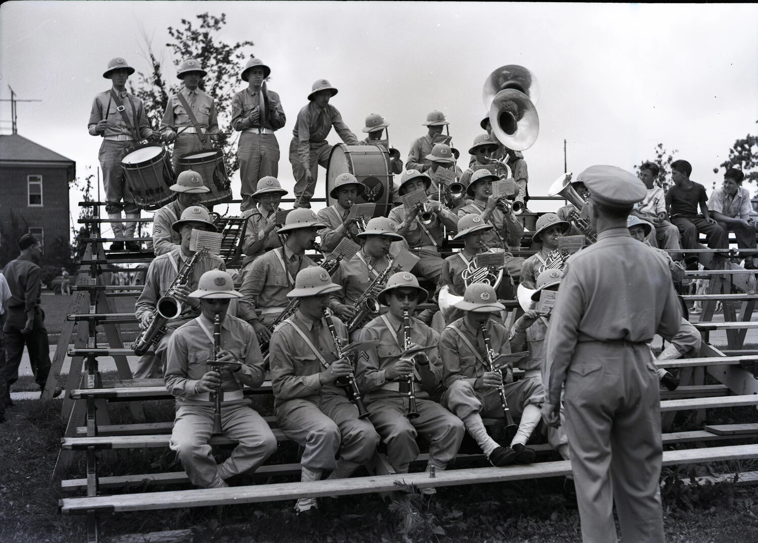 Military Band in Formation on Outdoor Risers, Conductor Directing, Pith Helmets