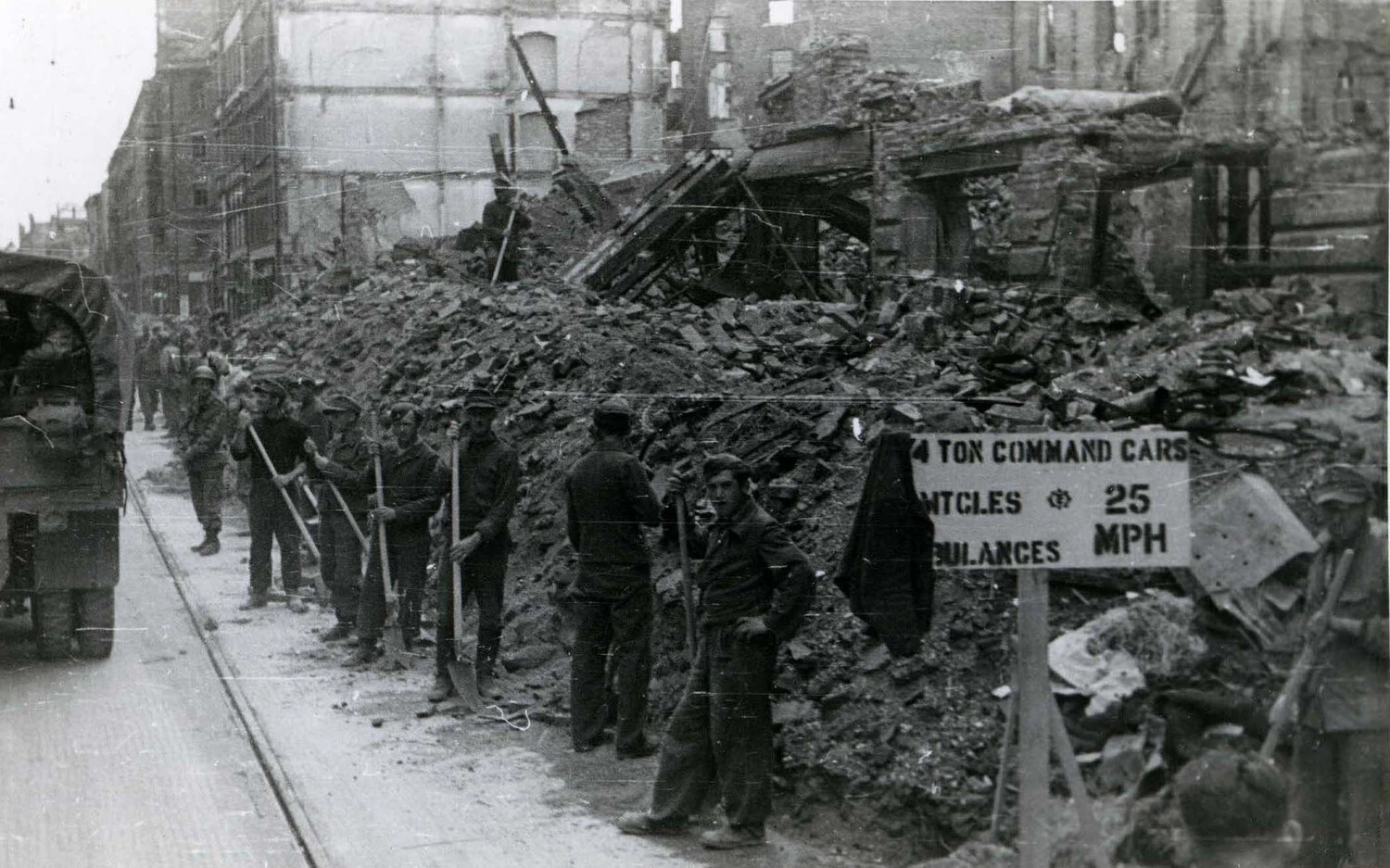 Civilian Laborers Clearing Rubble Beside U.S. Army Traffic Sign, Bomb-Damaged German City, WWII