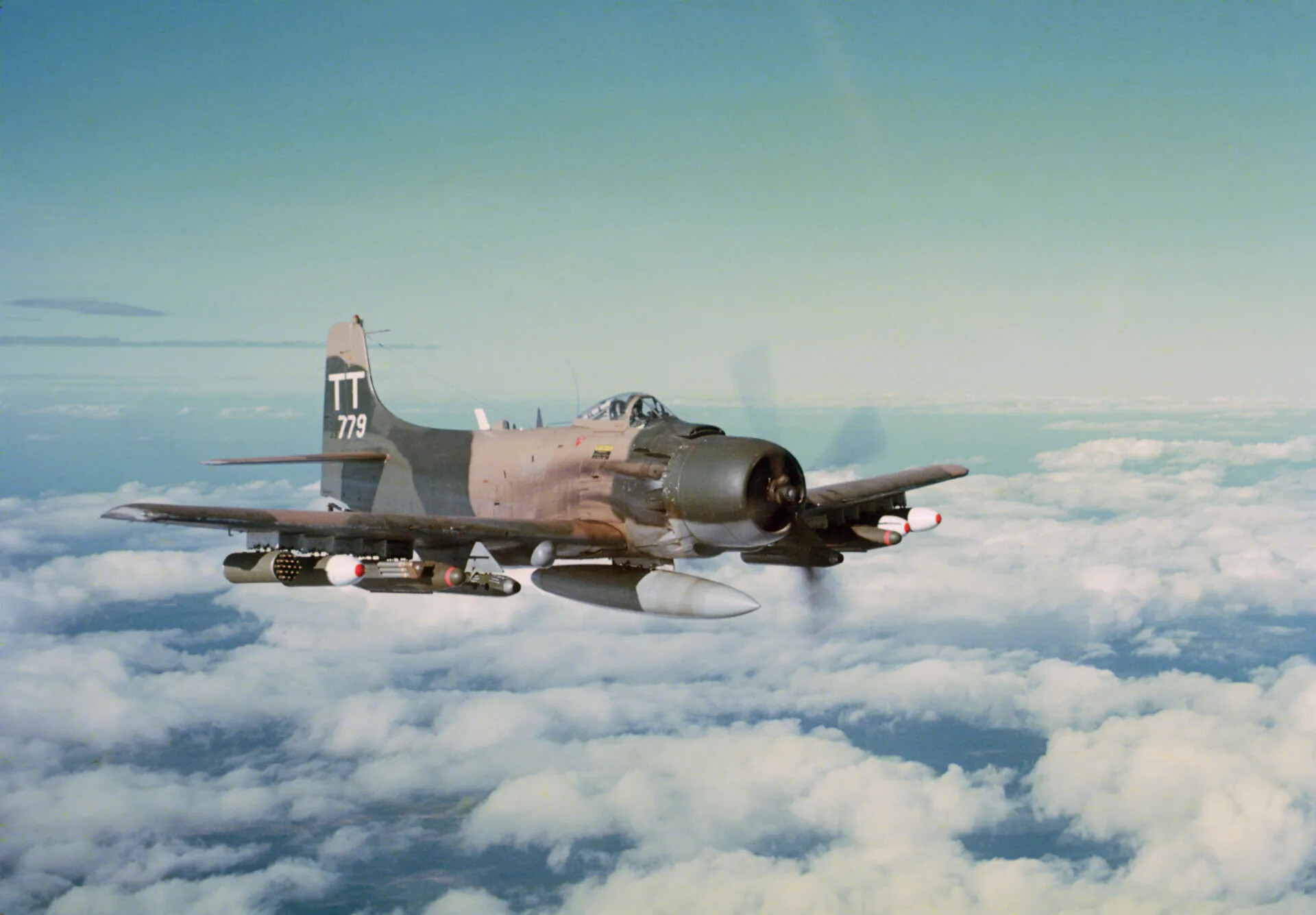 Armed Douglas A-1 Skyraider 'TT 779' in Flight Above Cloud Deck