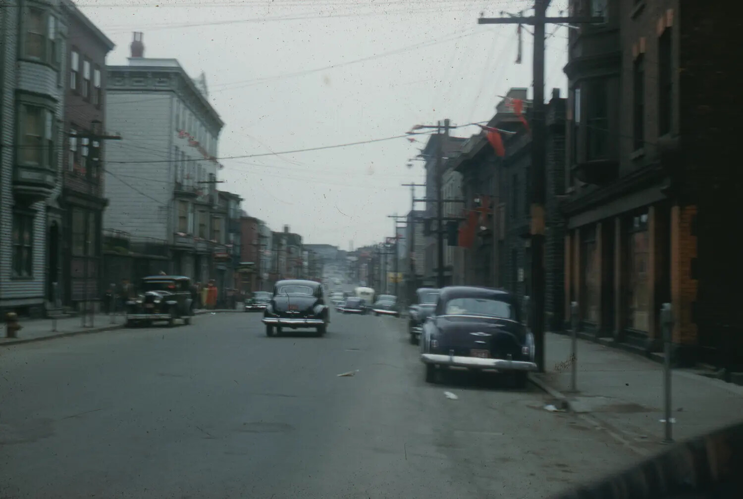 Urban Street Scene with Period Automobiles and Festive Bunting, Early 1950s