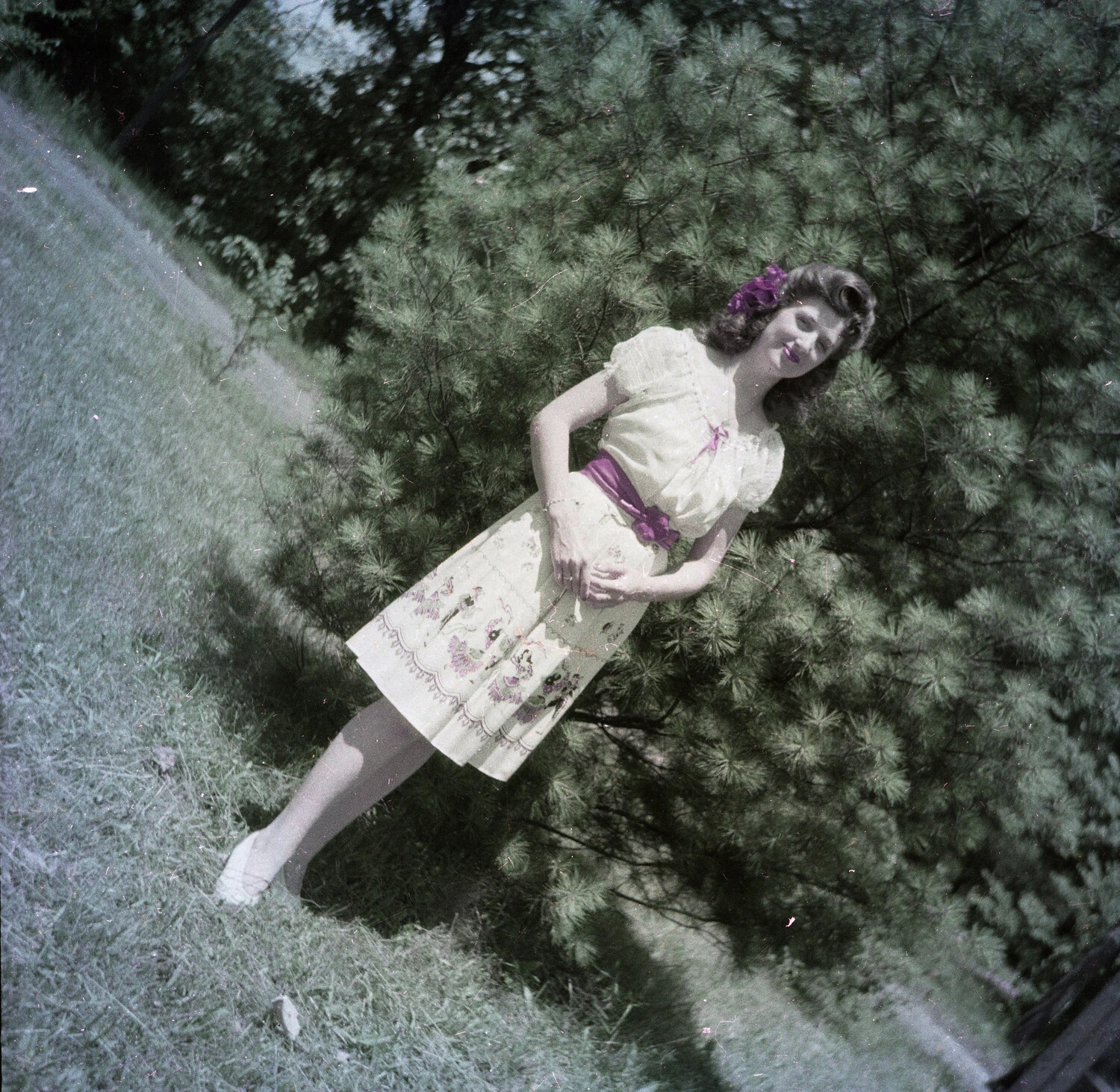 Portrait of a Young Woman in 1940s Dress Beside a Pine Tree