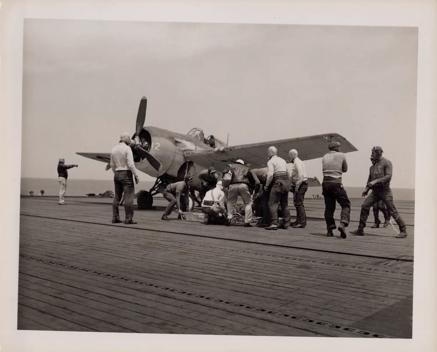 Deck Crew and Corpsmen Attend an Injured Airman Beside Fighter Aircraft No. 12 on Carrier Flight Deck