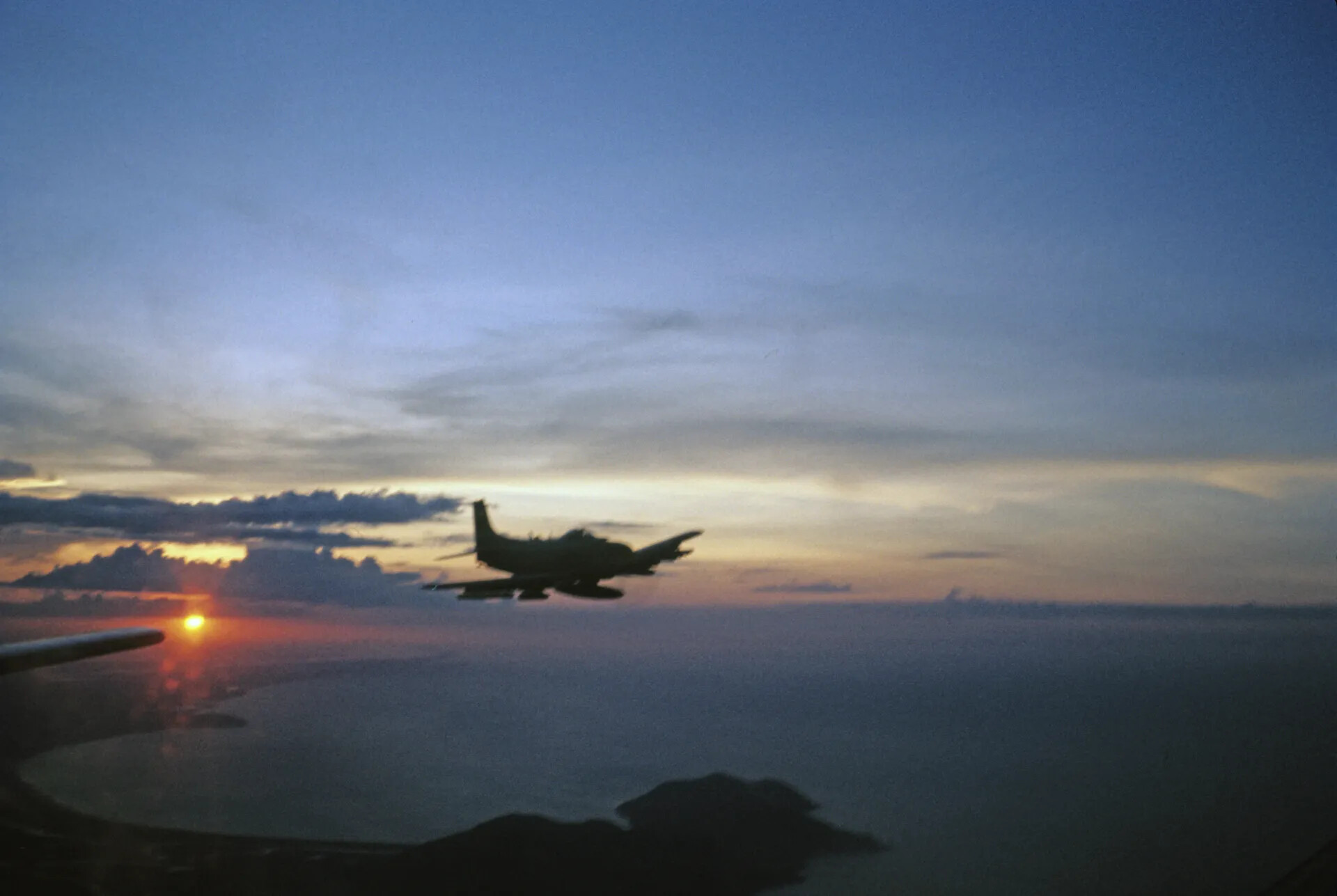 A-1 Skyraider Silhouetted at Sunset Over Vietnamese Coastline, circa June 1970