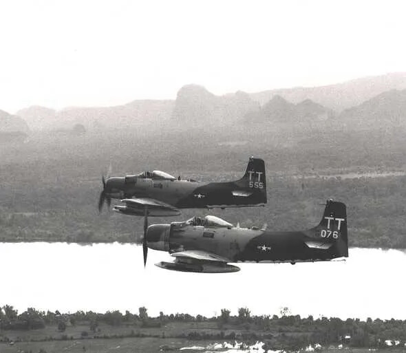 Two A-1 Skyraiders, Tail Codes TT 555 and TT 076, in Formation Over a River Valley — Low-Resolution Still, Banner Project Discard File