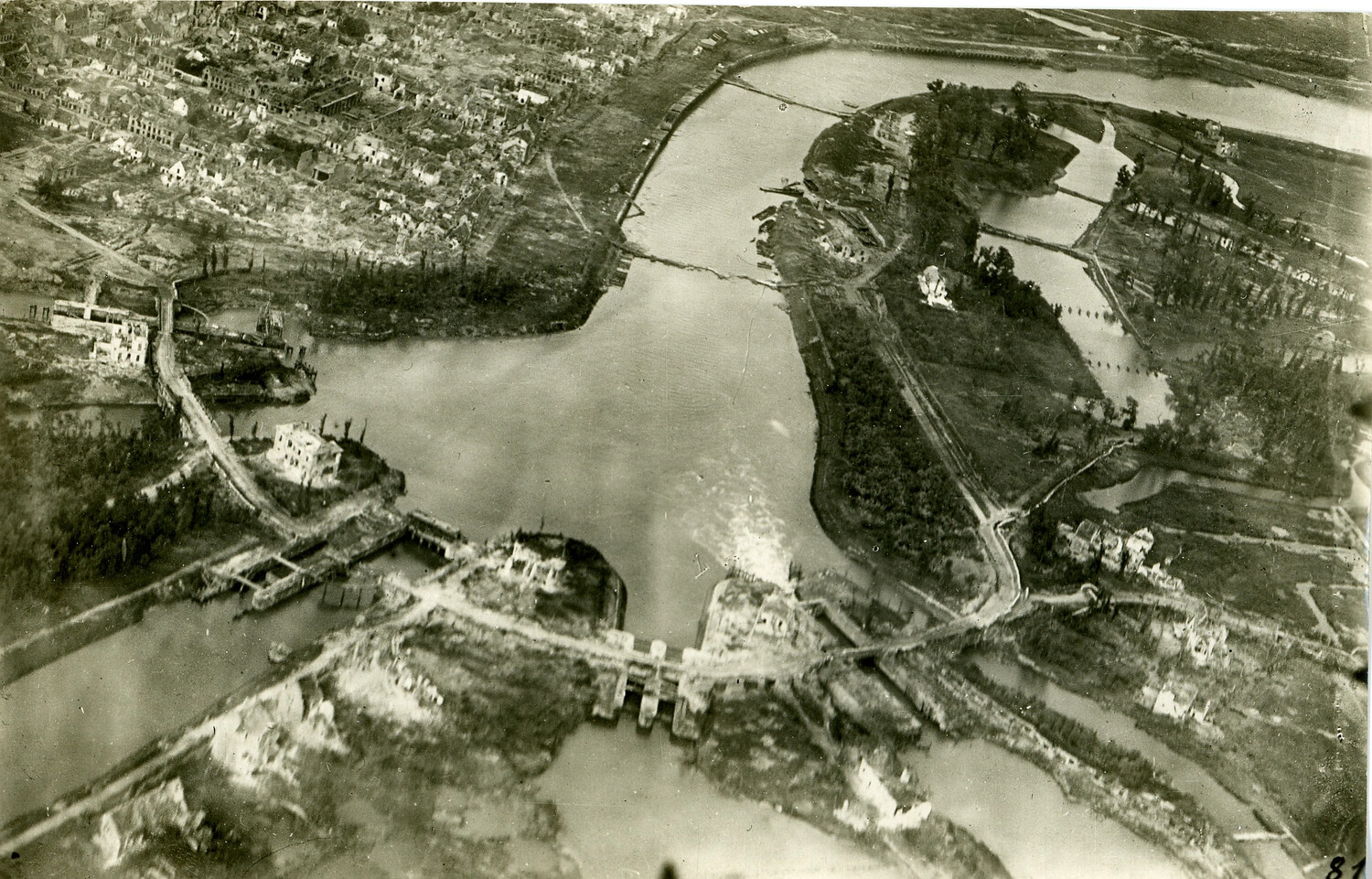 Aerial Reconnaissance Photograph of a War-Damaged European Riverside Town with Destroyed Bridge Crossings