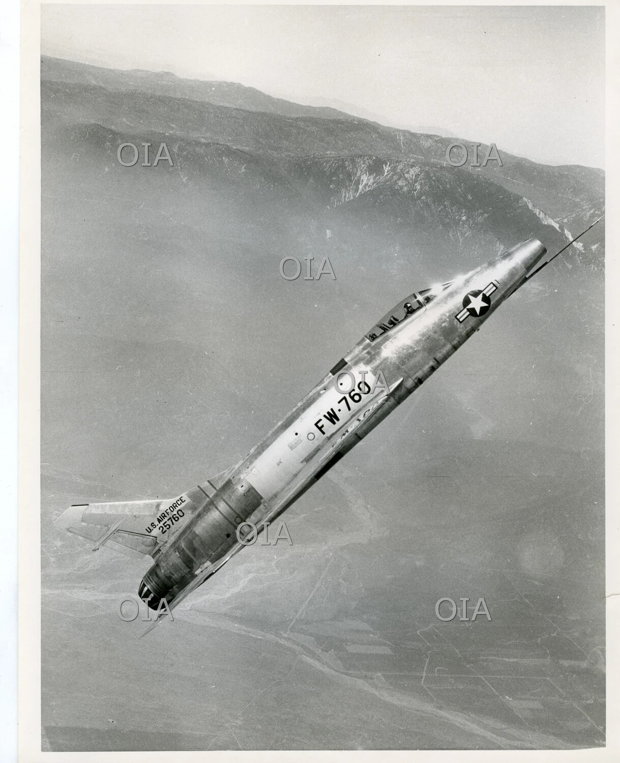 North American F-100 Super Sabre in Banked Flight Over Mountainous Terrain