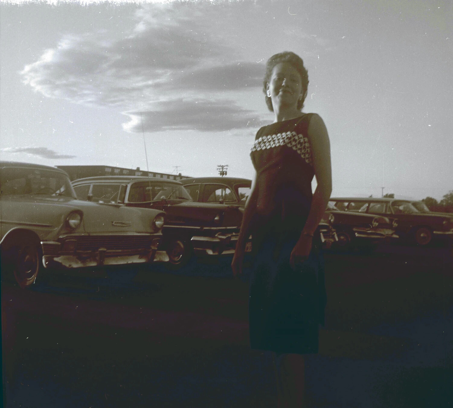 Backlit Portrait of a Young Woman in a Parking Lot with Mid-1950s Automobiles