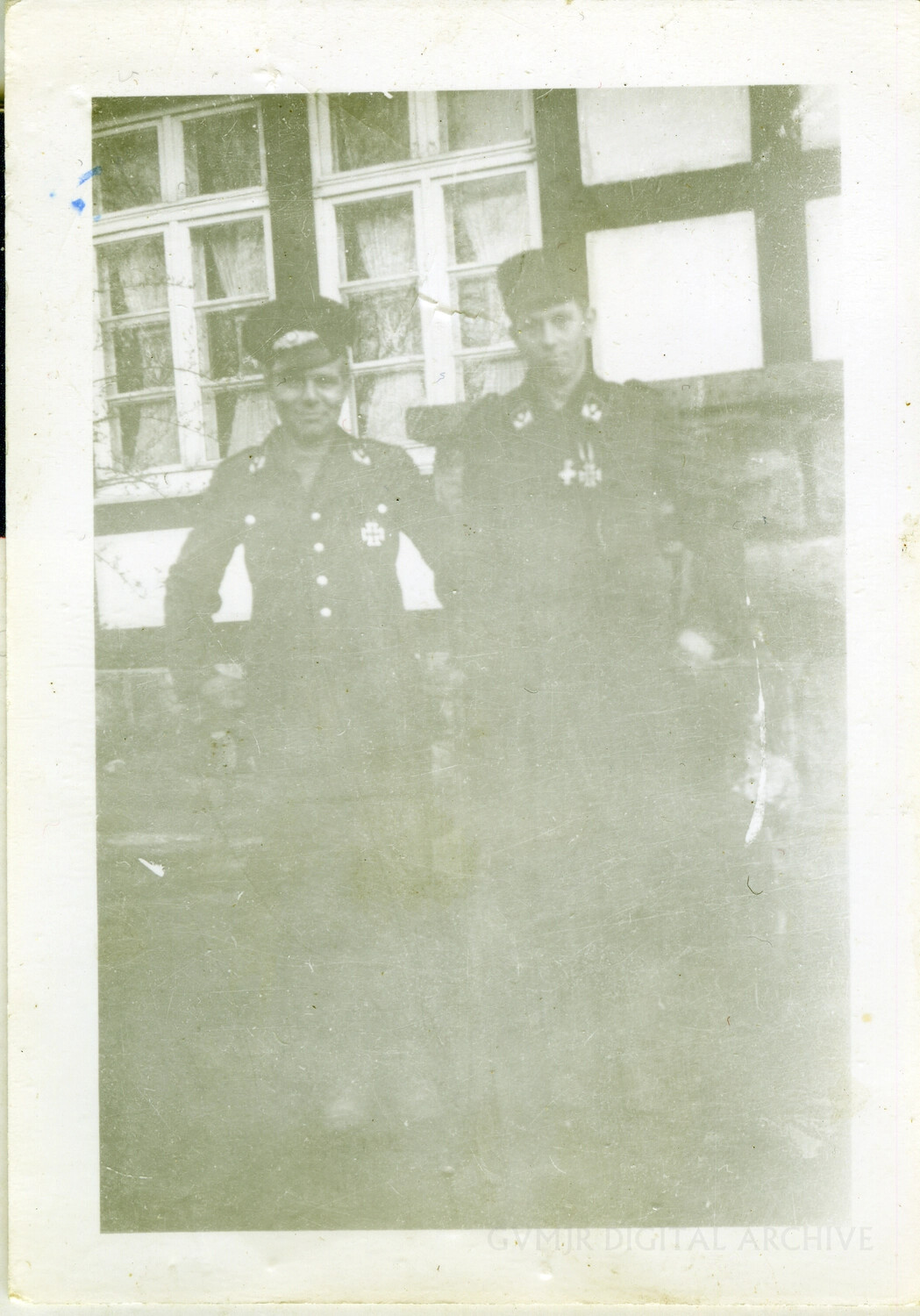 Two Uniformed Men, Possibly German Military Personnel, Before Half-Timbered Building, WWII Era