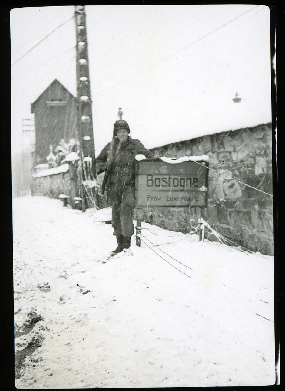 U.S. Soldier Beside 'Bastogne' Town Sign in Snow, Belgium, Winter 1944-1945