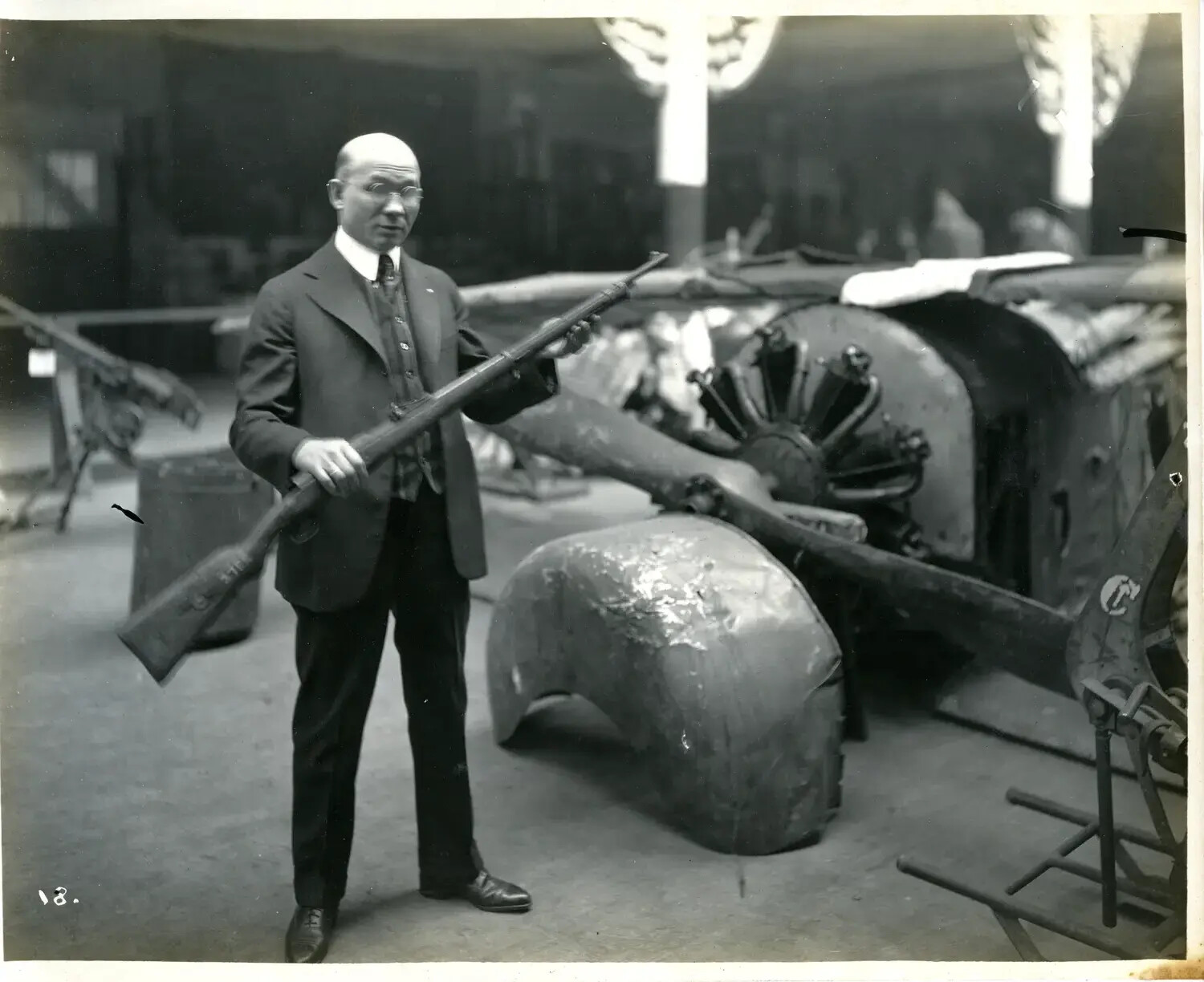 Civilian Holding Trophy Rifle Beside Wrecked Aircraft Engine, WWI Exhibition