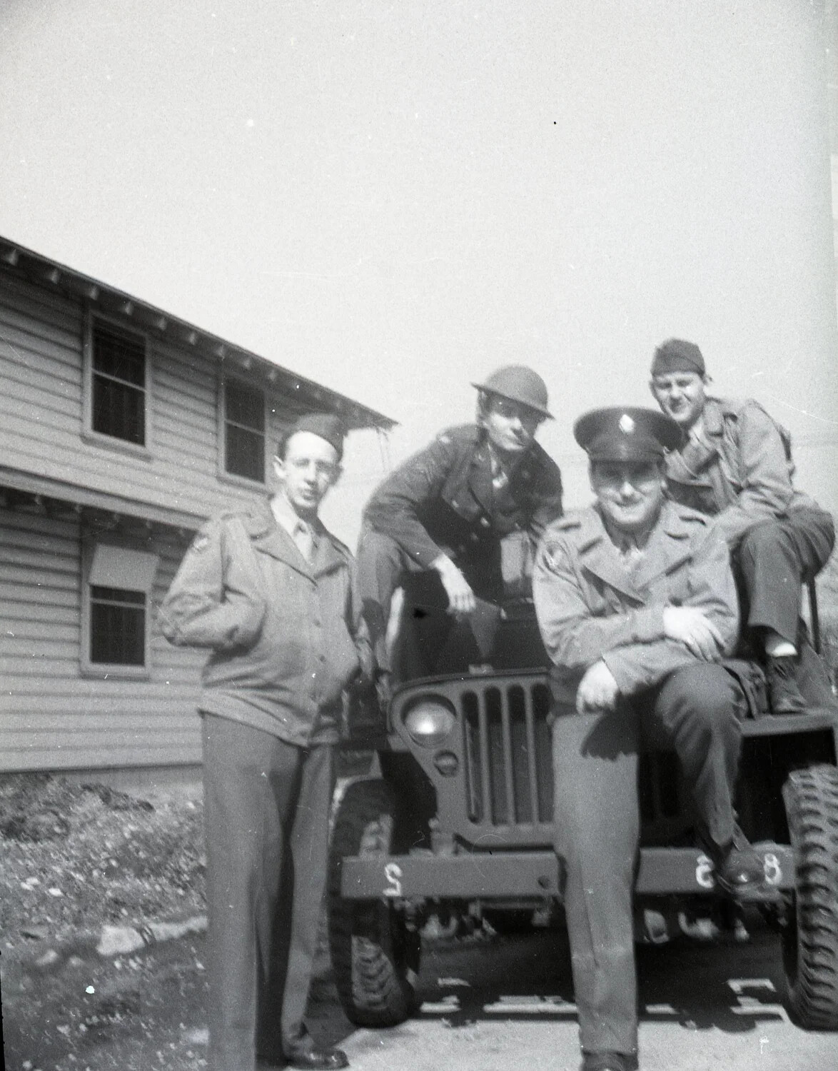 Four Servicemen Posed with Military Jeep, Barracks Backdrop
