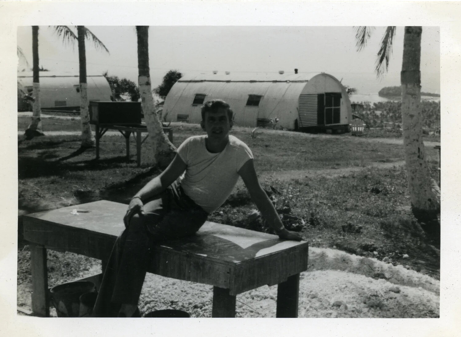 Serviceman Seated Near Quonset Huts, NATS Squadron VR-6, Agana, Guam