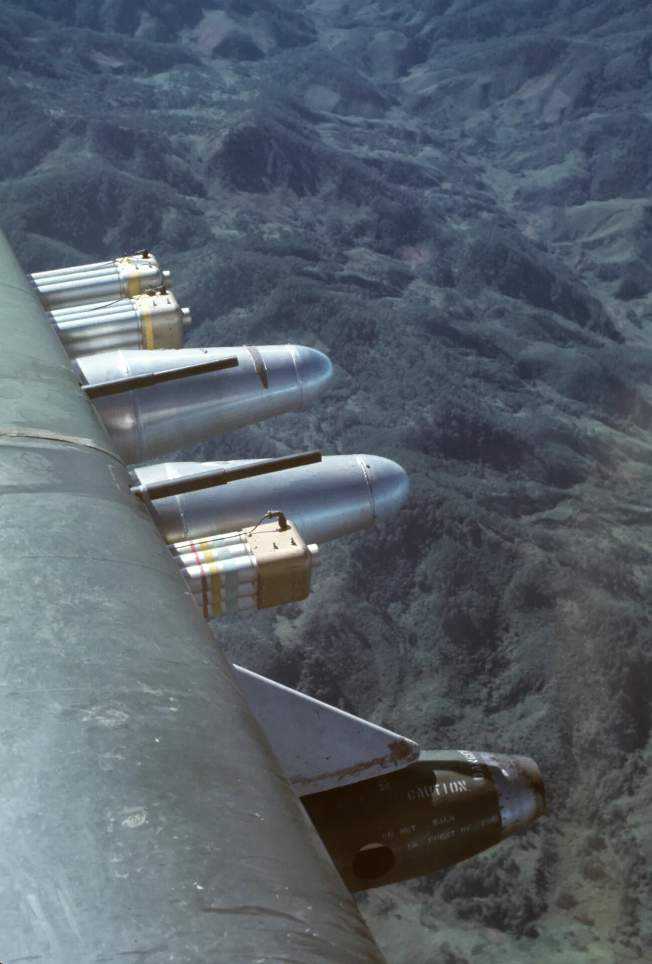 Wing-Mounted Ordnance Detail, Douglas A-1 Skyraider Over Mountainous Terrain, Southeast Asia, circa January 1970