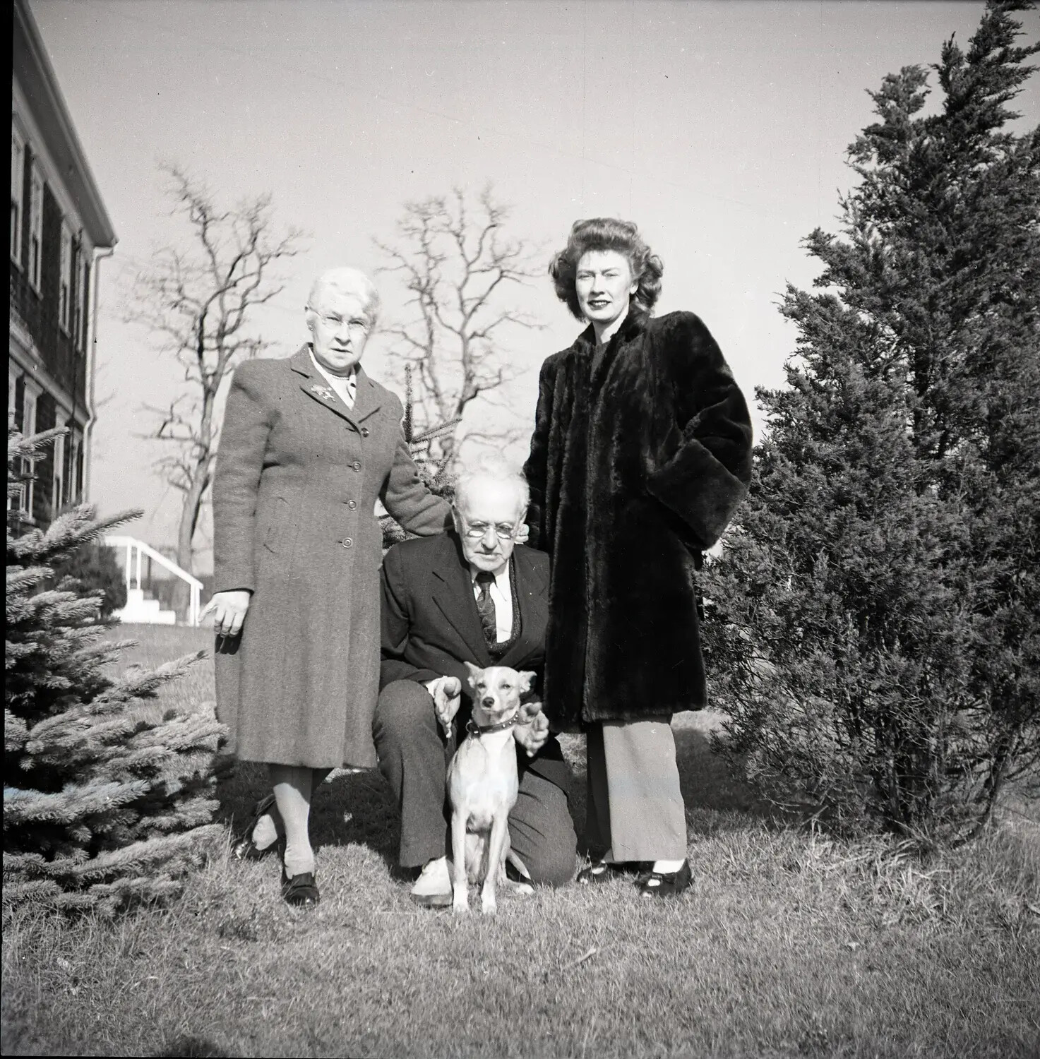 Three-Generation Family Group Portrait with Pet Dog on Institutional Grounds