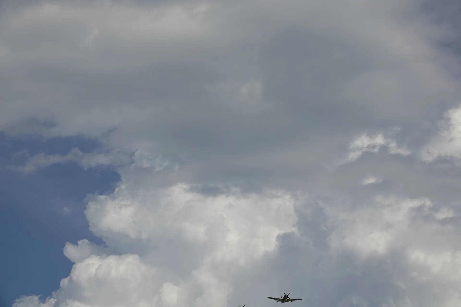Distant Warbird Against Towering Cumulus Clouds