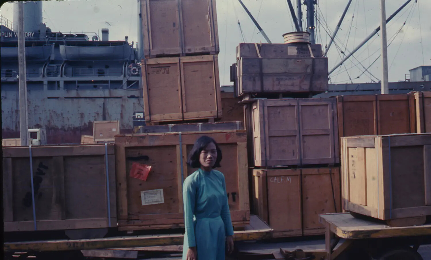 Vietnamese Woman Amid Military Cargo Crates at Saigon Dockside, with Victory-Class Cargo Ship, 1968
