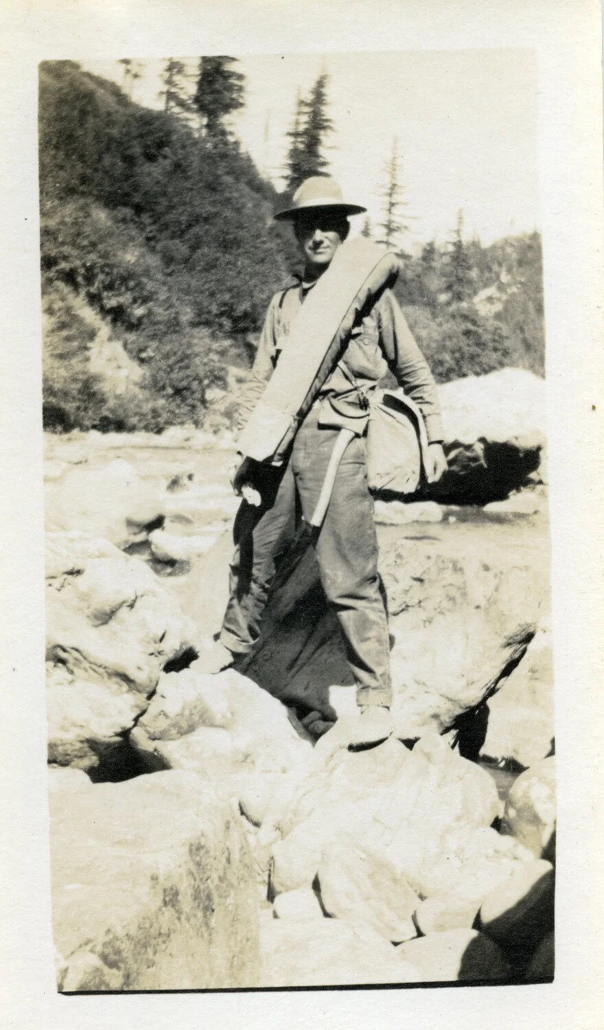 Hiker with Bedroll Crossing Rocky Riverbed, 'Willis and Party' Photo Series, 1921 — Willis W. Wagener Collection