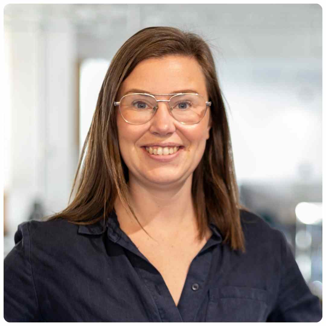 Profilbild av Hanna Rudolfsson som ler mot kameran. Hon har svart skjorta och glasögon.