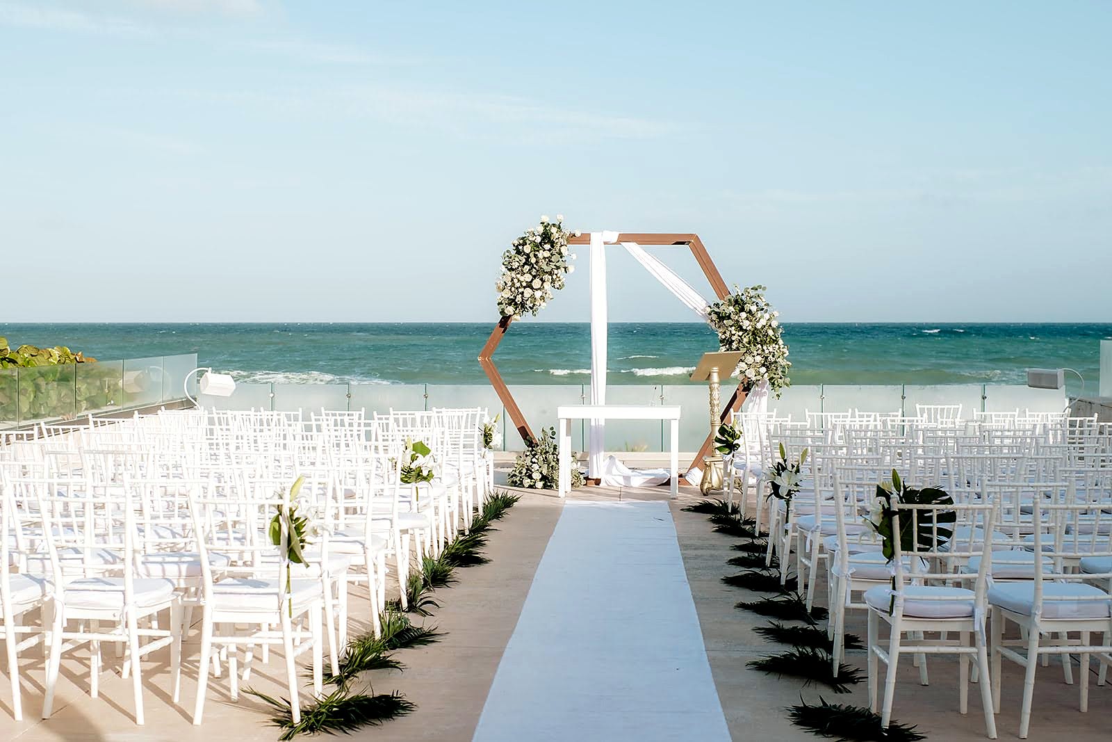 An intimate ocean-view ceremony setting with white chairs and flowers.