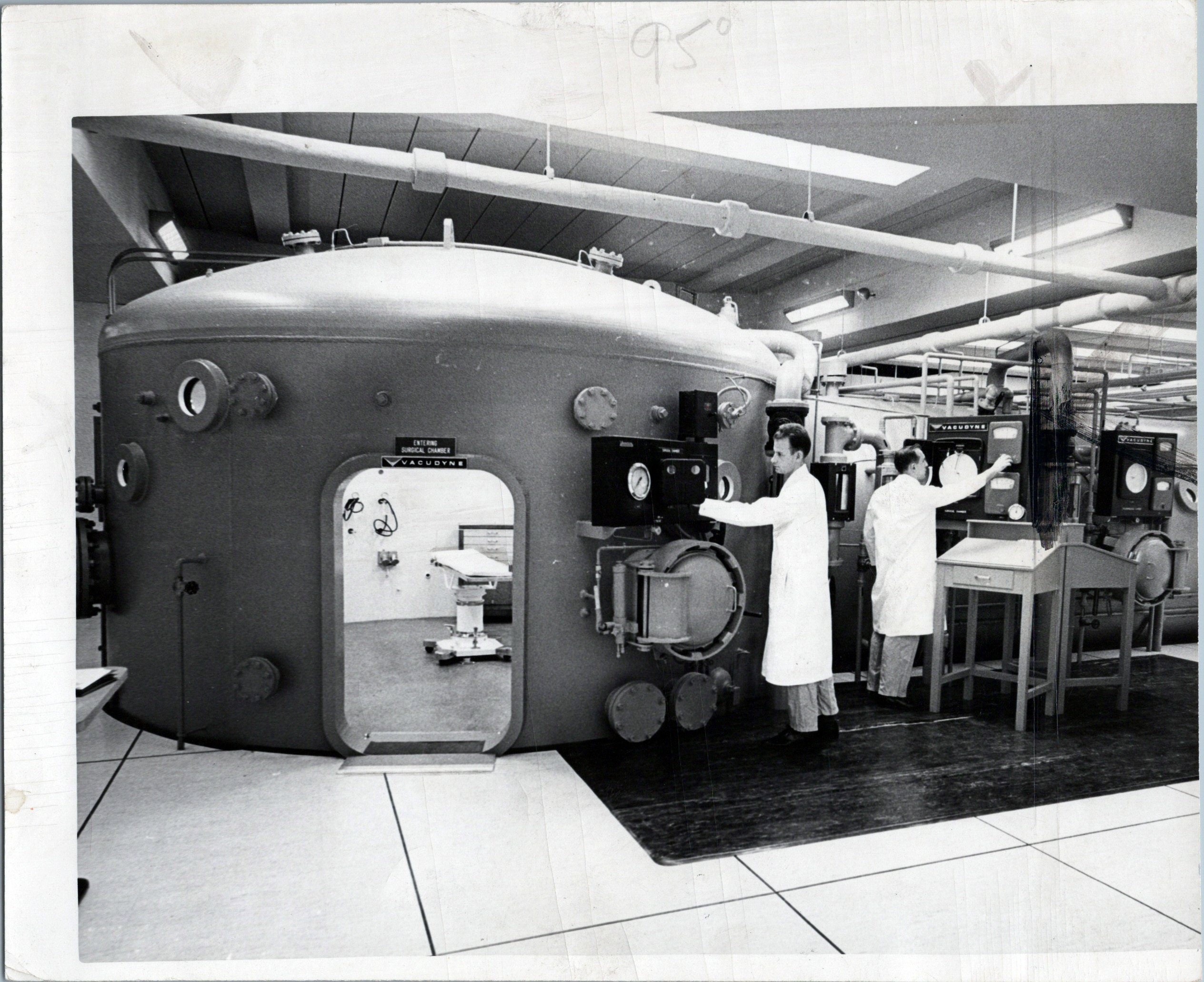 An archival photograph of a large hospital hyperbaric chamber and its control equipment