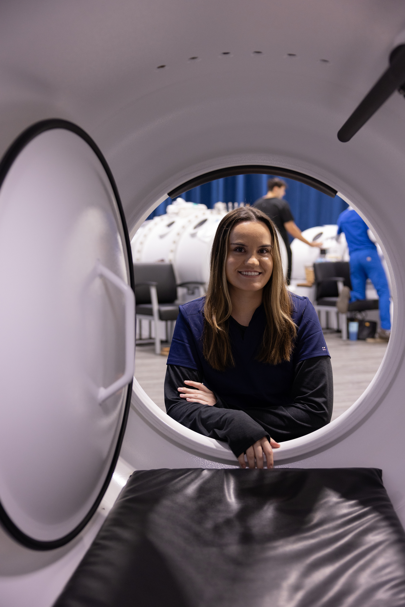An RX-O2 team member smiling through the open door of a hyperbaric chamber