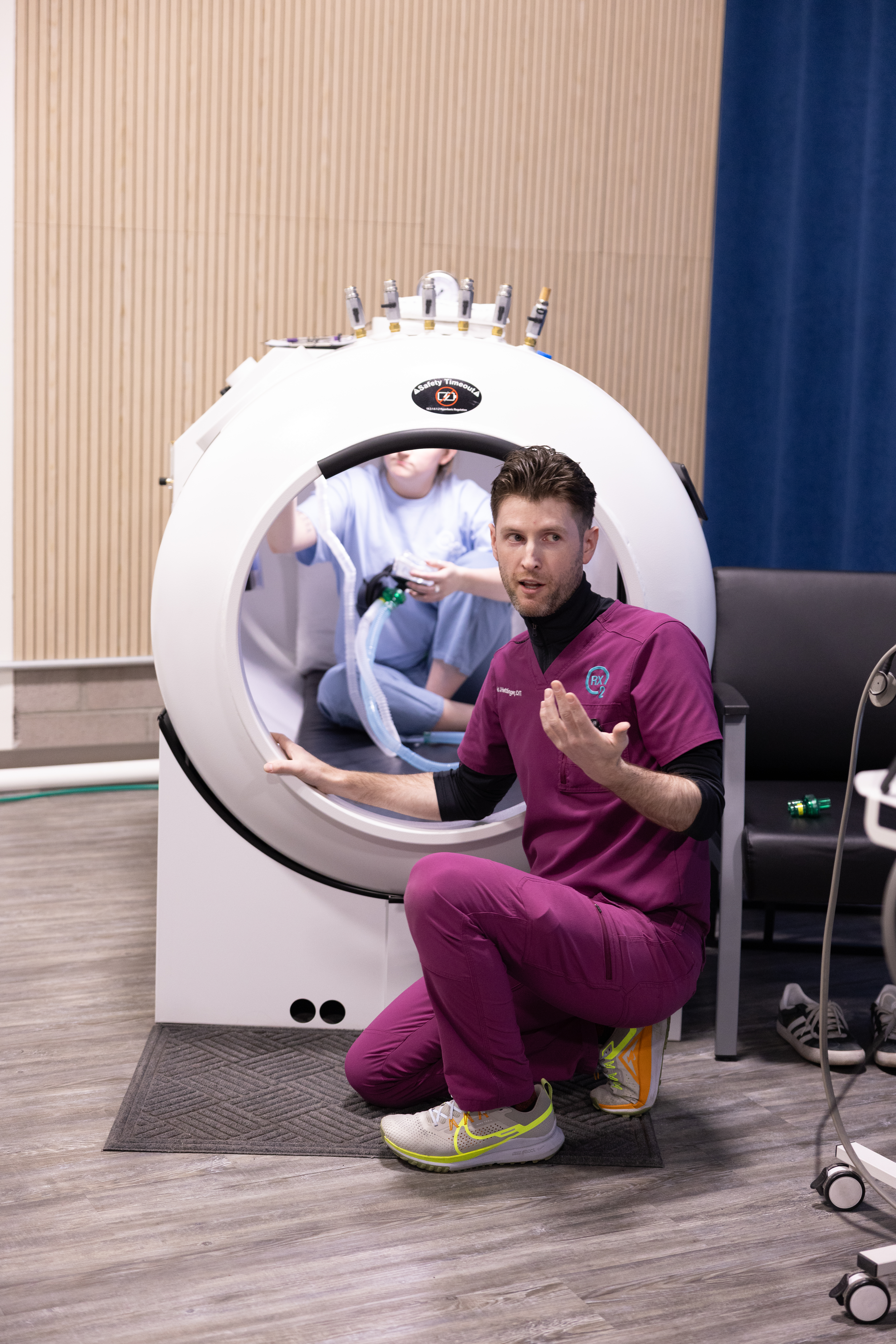 An RX-O2 team member explaining the chamber experience beside an open chamber