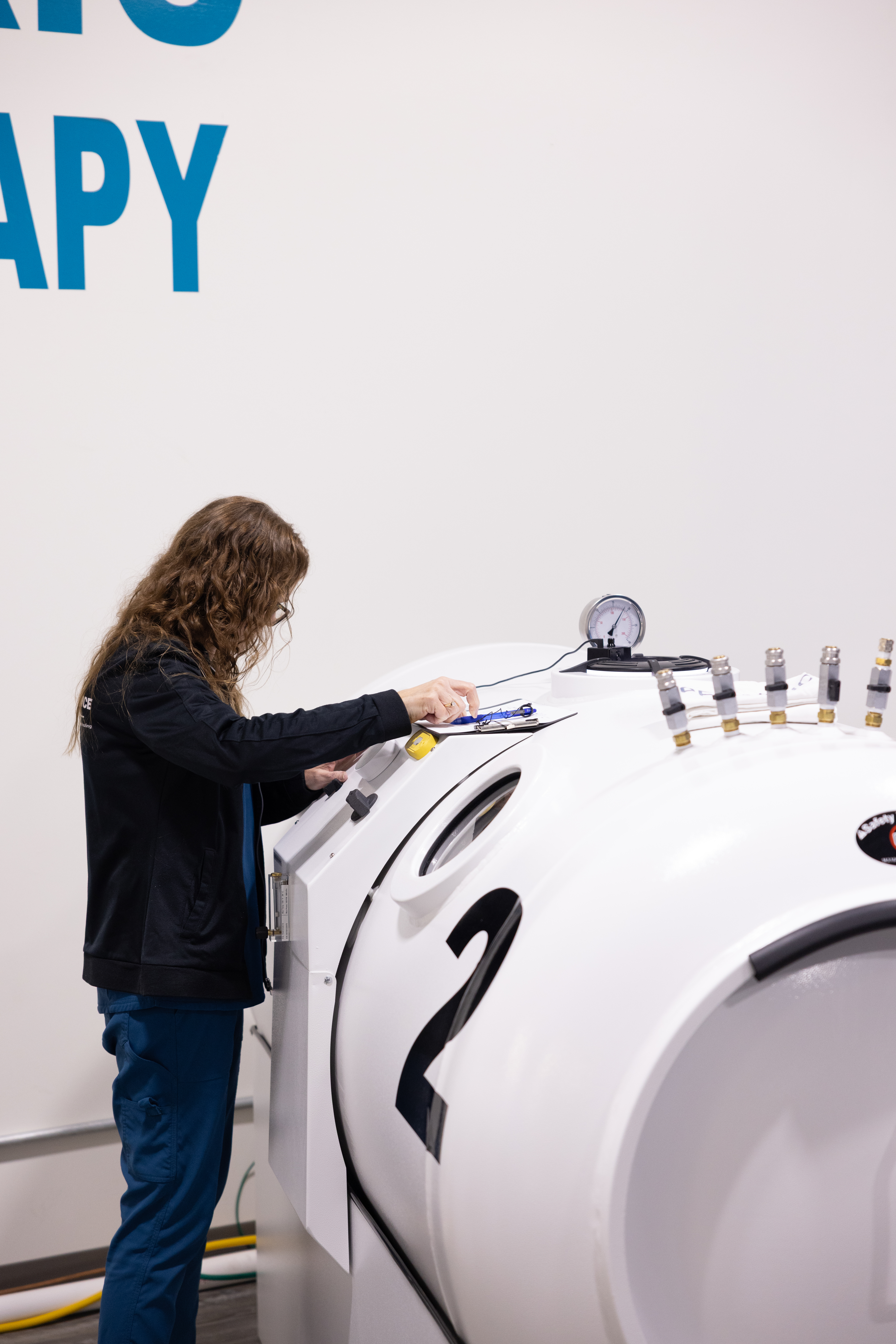 An RX-O2 team member reviewing a checklist beside hyperbaric chambers