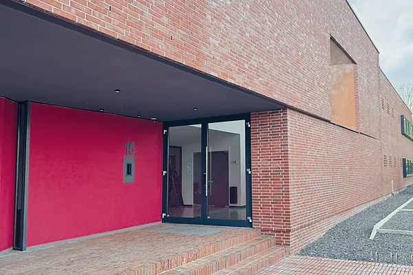 Eingang des Office Park mit roter Wand und Glastür
