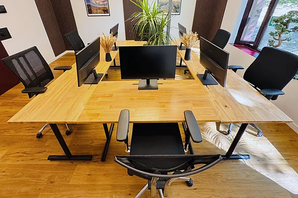 Arbeitsplätze mit Holztischen, Monitoren und ergonomischen Bürostühlen