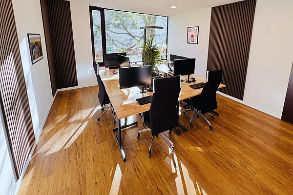 Sonniger Coworking-Raum mit Arbeitsplätzen und Holzboden