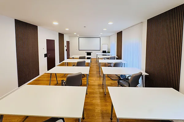 Seminarraum mit Tischreihen und Leinwand