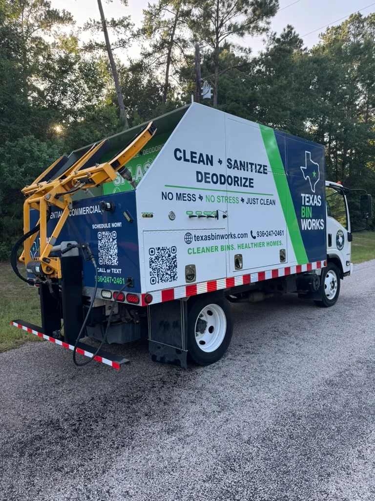 Rear view of a Texas Bin Works trailer with orange bins, showing 'Splash Zone' and contact information on a blue and green design.