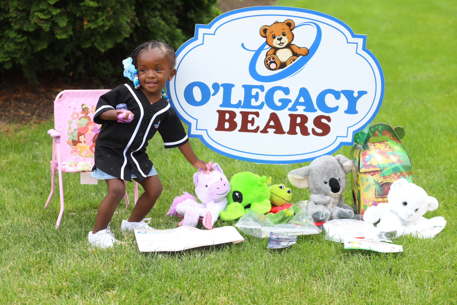 Child smiling beside a colorful assortment of O’Legacy Bears plush kits