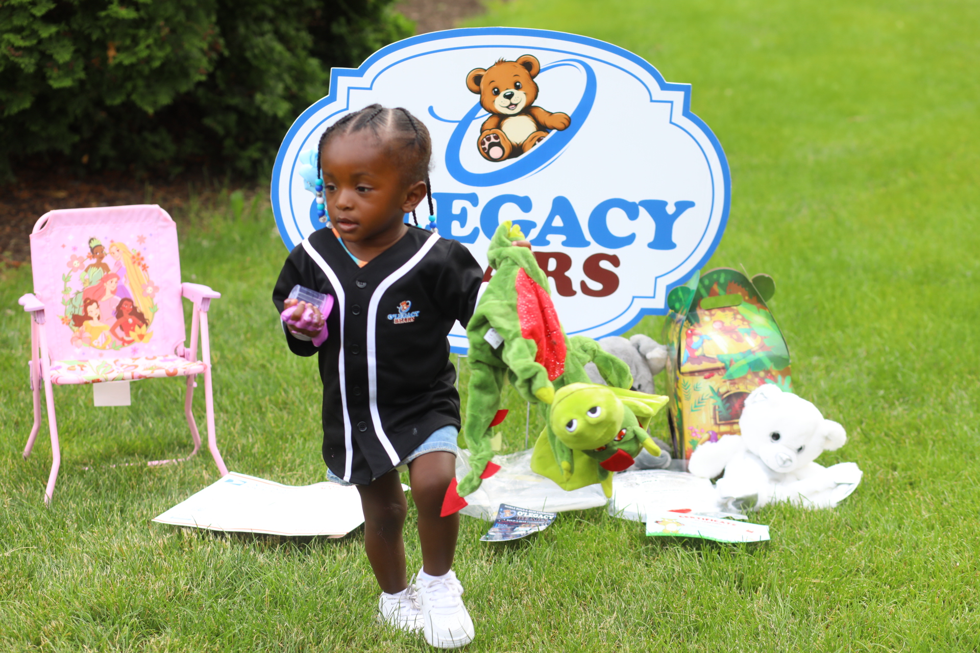 Child enjoying a green dragon plush at an O’Legacy Bears display