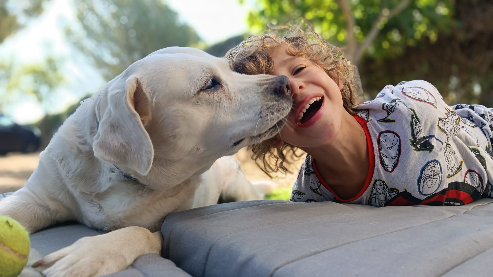 Un niño tumbado junto a su perro, riéndose