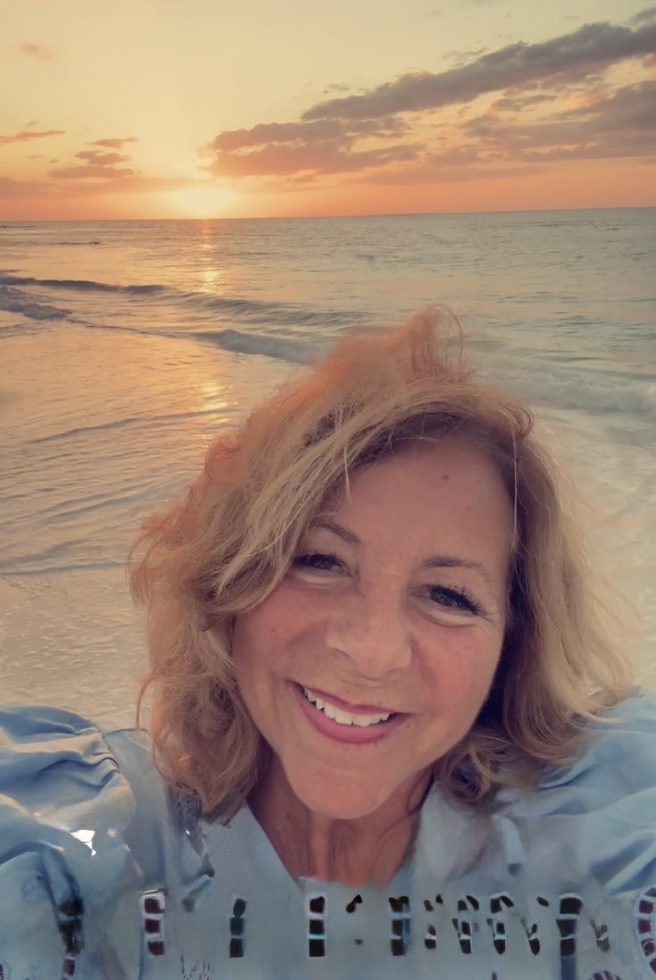 Coach Poppy smiling on the beach at sunset