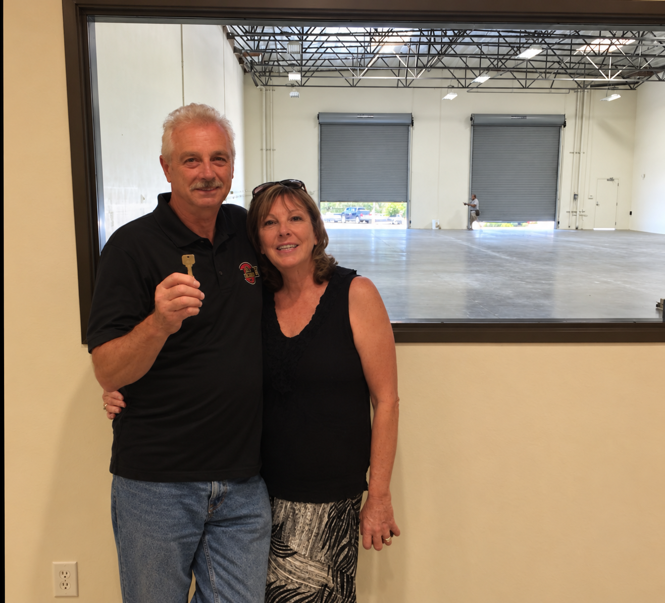 Michael holding a key beside Joy as they celebrate a company building milestone