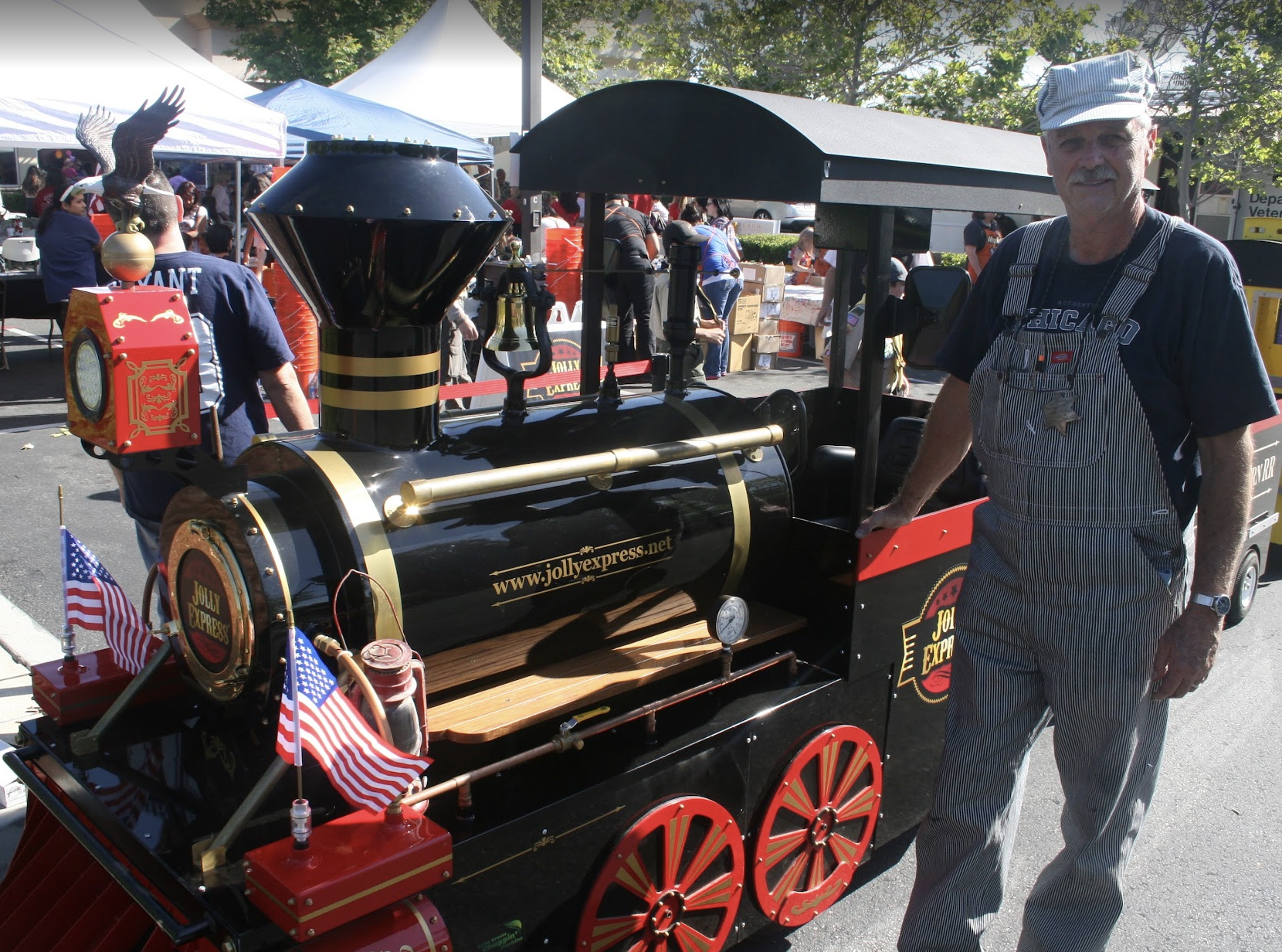 Michael in his train engineer uniform beside the Jolly Express Trackless Train