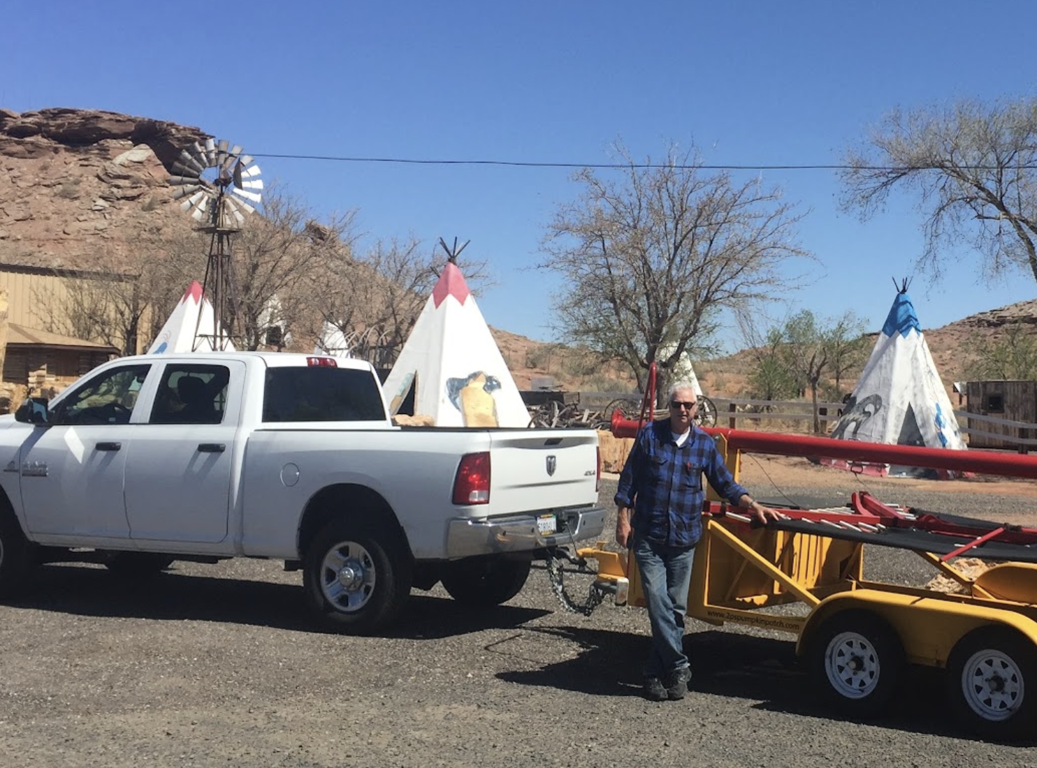 Michael standing beside his pickup truck and a trailer carrying a bungee trampoline