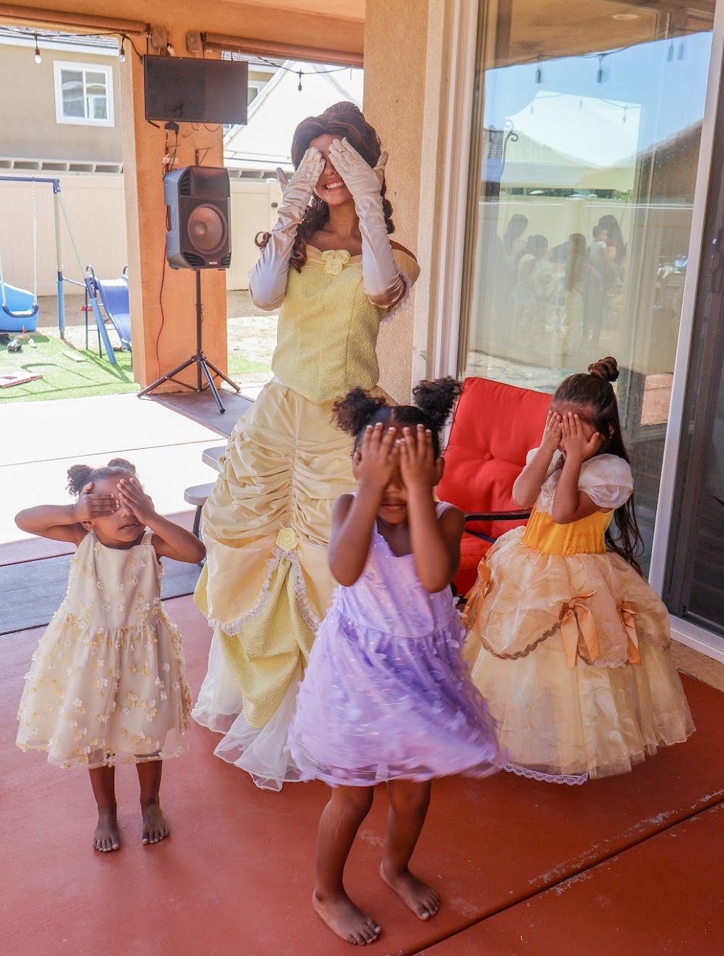 Belle and three children covering their eyes together during a playful birthday activity