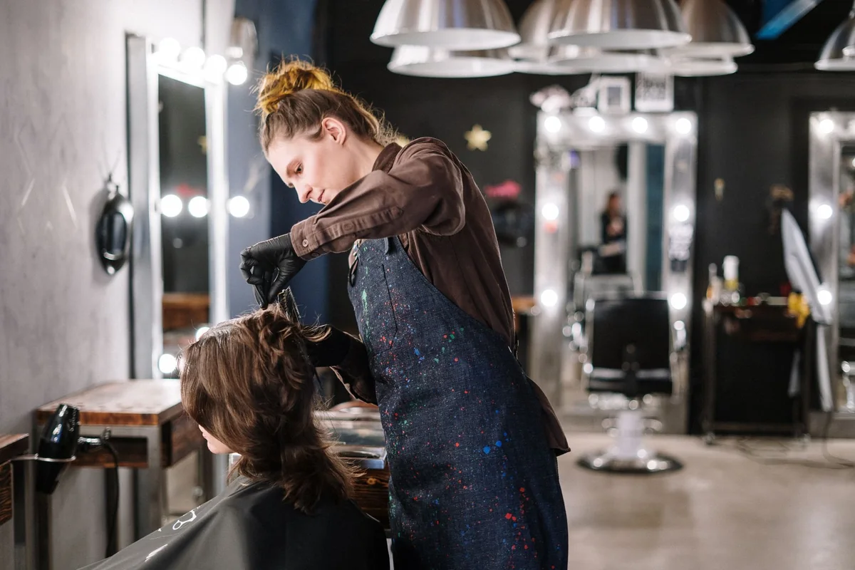 A hairdresser styling a seated client's hair in a salon